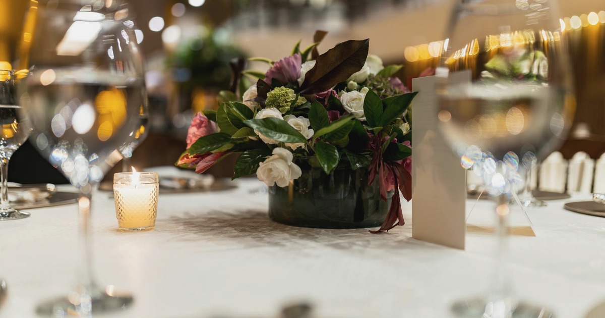 Premium-Event-Vorbereitung mit neutralen Einladungskarten, Kamera, Hospitality-Details und dunklem Eventtisch