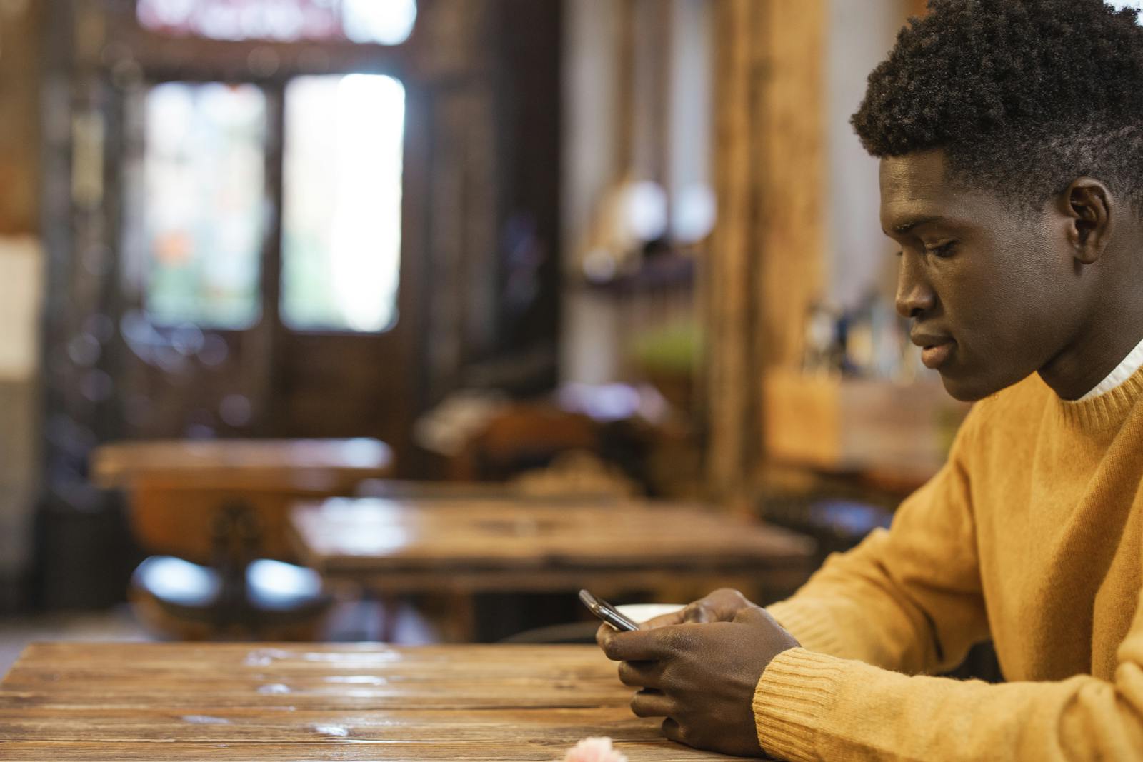 Junger Mann recherchiert am Smartphone im Café, sinnbildlich für Bewerber-Suchverhalten 2026