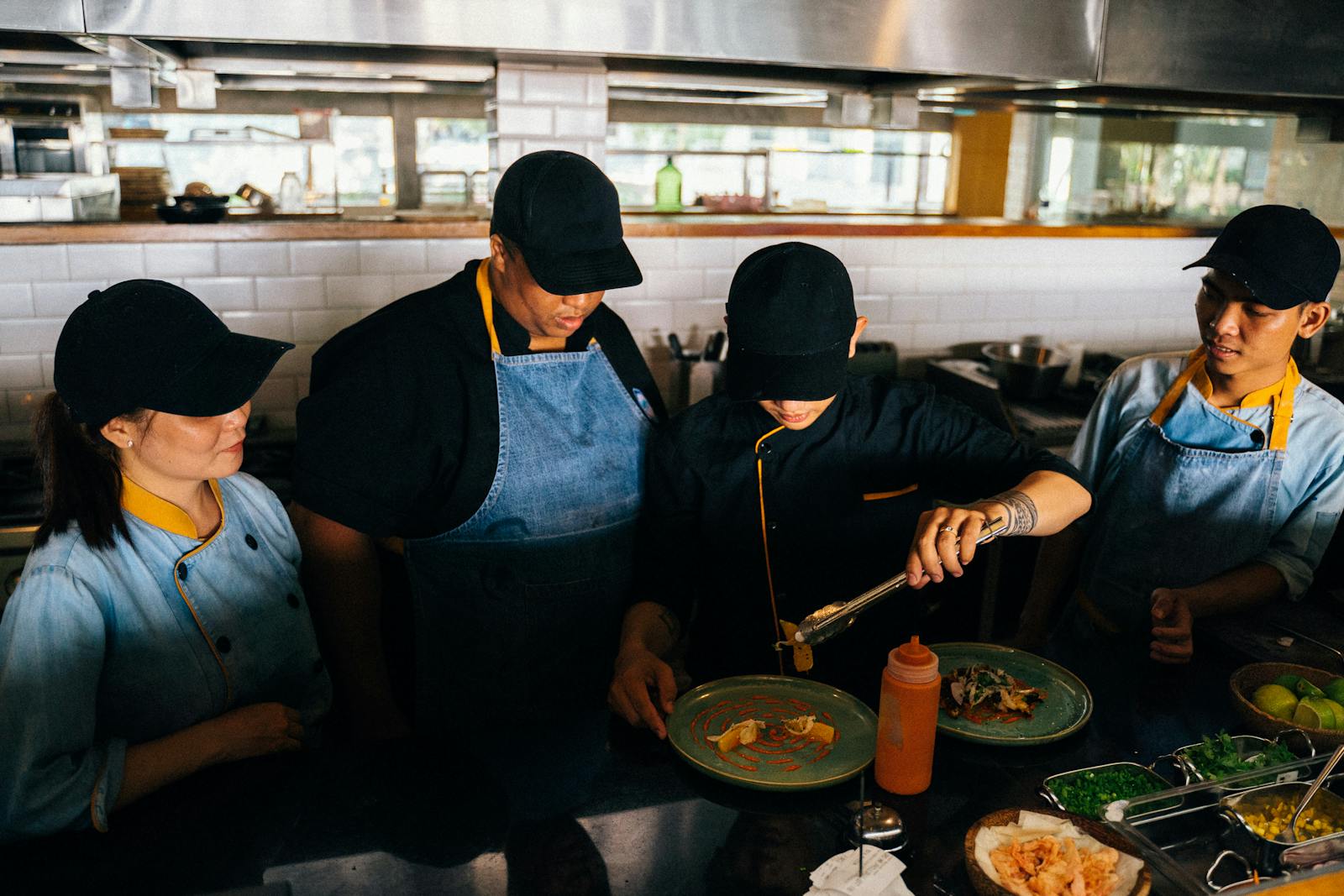 Sous-Chefs in Restaurantküche bereiten gemeinsam Teller zu, Schichtarbeit als Team